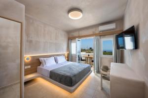 a bedroom with a bed and a television and a table at Aelia Luxury Suites in Karterados