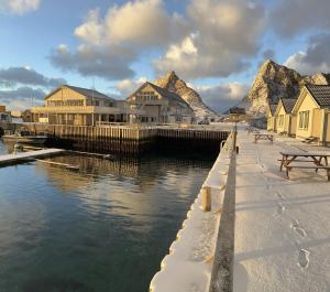a body of water with houses and a pier with snow on it at Lofoten Værøy Bryggehotell AS in Værøy