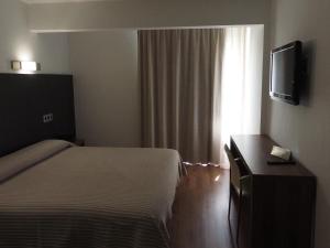 a bedroom with a bed and a tv and a window at Hotel Astoria Park in Lloret de Mar