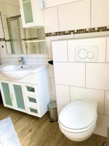 un bagno bianco con un water e un lavandino di Ferienwohnung Anne a Eppenrod Altre 32 foto