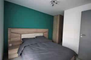 1 dormitorio con 1 cama con pared azul en L'Aurore, en Gérardmer