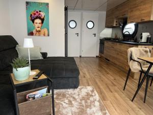 a living room with a black couch and a kitchen at Hausboot mit Motorboot in Heiligenhafen