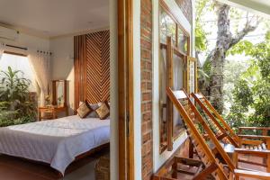 a bedroom with a bed and a balcony at Little Garden Bungalow in Phu Quoc