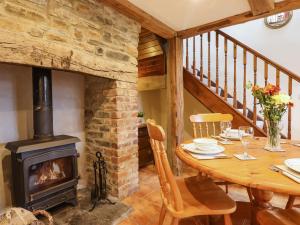 巴恩斯特珀爾的住宿－Ridge Cottage，一间带木桌和燃木炉的用餐室