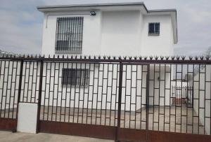 uma cerca em frente a um edifício branco com janelas em Bonita y cómoda casa cerca del consulado. em Ciudad Juárez
