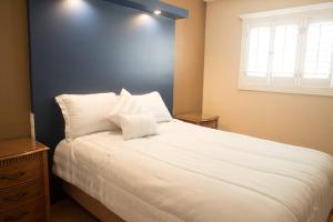um quarto com uma grande cama branca e uma parede azul em Bonita y cómoda casa cerca del consulado. em Ciudad Juárez