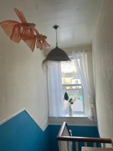 Habitación con ventana y 2 mariposas colgando del techo en The Shell House en Falmouth