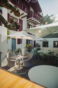 un restaurante con mesas, sillas y sombrillas en Hôtel Briketenia, en Guéthary