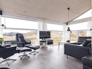 a living room with a couch and chairs and a tv at 12 person holiday home in Pandrup in Rødhus