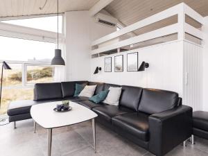 Rødhusにある12 person holiday home in Pandrupのリビングルーム(黒い革張りのソファ、テーブル付)