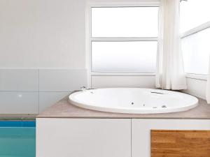 ein weißes Bad mit einer weißen Badewanne und einem Fenster in der Unterkunft 12 person holiday home in Pandrup in Rødhus