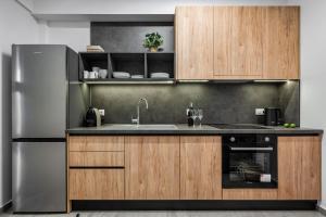 Coel Luxury Suites by RentalsPro Services - Potidea Halkidiki في نيا بوتيدايا: مطبخ مع دواليب خشبية وثلاجة حديد قابلة للصدأ