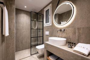 Coel Luxury Suites by RentalsPro Services - Potidea Halkidiki في نيا بوتيدايا: حمام مع حوض ومرحاض ومرآة