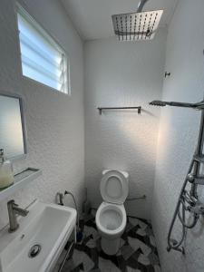 een witte badkamer met een wastafel en een toilet bij A’Casa Cottage in Kuala Terengganu