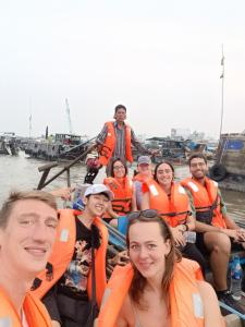a group of people in orange life jackets on a boat at Enjoy Mekong Hostel in Can Tho