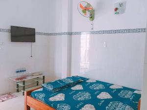 a bedroom with a bed with blue sheets and a tv at Nhà nghỉ Thiên Thanh 1 in Long Hai