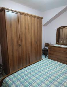 1 dormitorio con 1 cama y armario de madera en La casa nel Borgo, en Bella