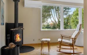 a living room with a fireplace and a chair at Awesome Home In Væggerløse With Kitchen in Marielyst