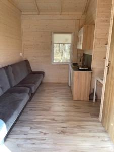 ein Wohnzimmer mit einer Couch in einem winzigen Haus in der Unterkunft Domki i Pole Namiotowe Pod Sosnami in Olsztyn