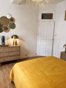 a bedroom with a yellow bed and a white door at Appartement chaleureux au centre du village in Montesquieu-Volvestre