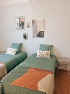 2 camas en una habitación con fotos en la pared en Appartement chaleureux au centre du village, en Montesquieu-Volvestre