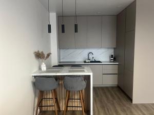 una cocina con armarios blancos y una barra con taburetes en Saules apartamentai, free parking, en Klaipėda