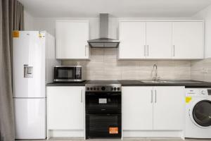 uma cozinha com armários brancos, um fogão e um micro-ondas em Stylish Studio room in Mill Hill em Edgware