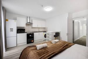 a bedroom with a bed and a kitchen with white cabinets at Stylish Studio room in Mill Hill in Edgware