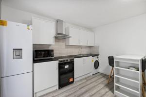 a kitchen with white appliances and white cabinets at Stylish Studio room in Mill Hill in Edgware