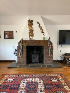 a living room with a brick fireplace and a tv at Orchard Cottage in Montrose
