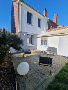 un patio avec trois bancs et un bâtiment blanc dans l'établissement La ScarpeHouse - Douai - Wifi, à Douai