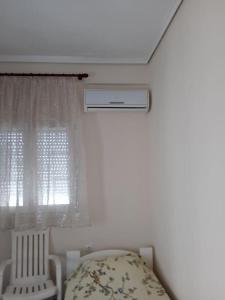 une chambre avec un lit, une fenêtre et une chaise dans l'établissement Apartment Aleksadra, à Paralia Katerinis