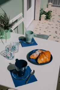 einen Tisch mit blauen Tellern, Tassen und Croissants in der Unterkunft A Casa Scipione in Formia