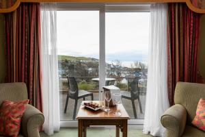 uma sala de estar com uma mesa e vista para uma varanda em Fernhill Hotel em Portpatrick