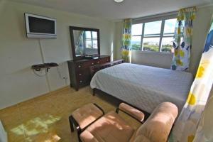 a bedroom with a bed and a chair and a television at Pena Mar Ocean Club Best Views in Fajardo