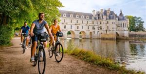 três pessoas a andar de bicicleta por um caminho em frente a um castelo em Studio 1 ATELIER VINCI em Amboise