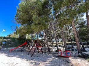 un parque infantil con columpios rojos y árboles en Mobile Home Bubamara, en Drage