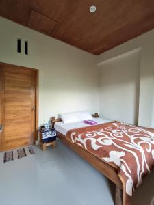 a bedroom with a large bed and a wooden door at Made Oka Budget Room in Munduk