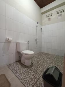 a bathroom with a toilet and a trash can at Made Oka Budget Room in Munduk