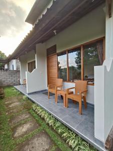 eine Terrasse eines Hauses mit 2 Stühlen und einem Tisch in der Unterkunft Made Oka Budget Room in Munduk