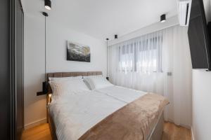 Schlafzimmer mit einem Bett mit weißer Bettwäsche und einem Fenster in der Unterkunft Villas Residence 360 in Trogir