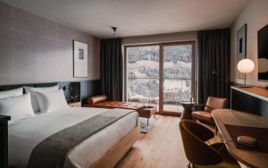 pokój hotelowy z łóżkiem i dużym oknem w obiekcie The Comodo Bad Gastein, a Member of Design Hotels w mieście Bad Gastein