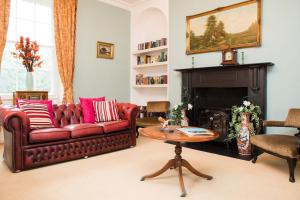 a living room with a red couch and a fireplace at The Grange Manor House, Norfolk in Setchey