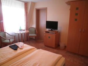 a bedroom with a bed and a tv and a table at Hotel "Pension" Strandkorb in Norddeich