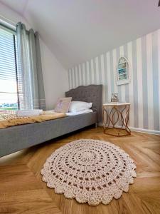 a bedroom with a bed and a rug on a wooden floor at Karwia Plaza - Apartments - Domki z basenem, jacuzzi i sauną in Karwia