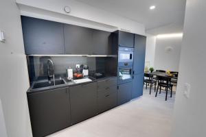 a kitchen with black cabinets and a dining room at Best location in Tampere! Modern city apartment, 2rooms, kitchen and balcony in Tampere