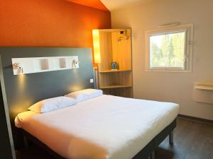 a bedroom with a large white bed with an orange wall at ibis budget Carcassonne La Cité in Carcassonne
