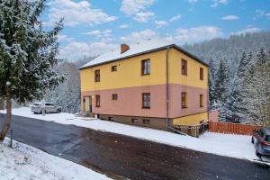 una casa amarilla y rosa en la nieve en Apartmanovy dům Bublajda, en Bublava