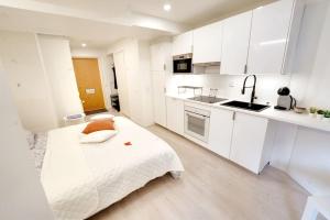 a kitchen with white cabinets and a bed in a room at Upea yksiö+parveke. Ihastu, parhaalla paikalla. in Tampere