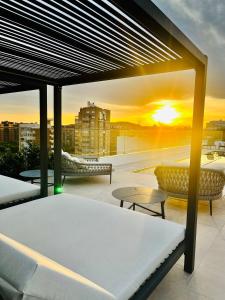 einen Balkon mit einem Bett und Tischen und einem Sonnenuntergang in der Unterkunft Port Alicante City & Beach in Alicante